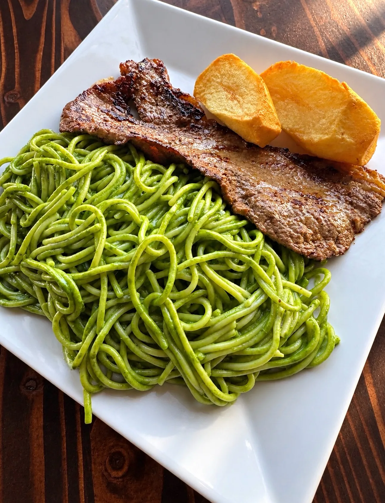Tallarín verde con bistec — green spaghetti with grilled steak and a fried potato